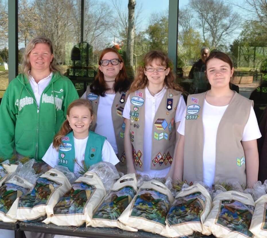 5 Girl Scouts smiling in front of a table