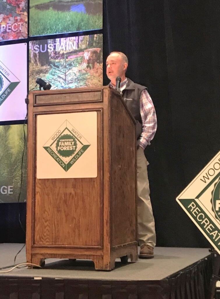 Michael Hughey standing behind a podium on stage at the American Tree Farm System awards.
