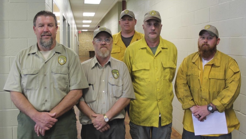 Five men standing in a hallway, wearing forestry service insignias
