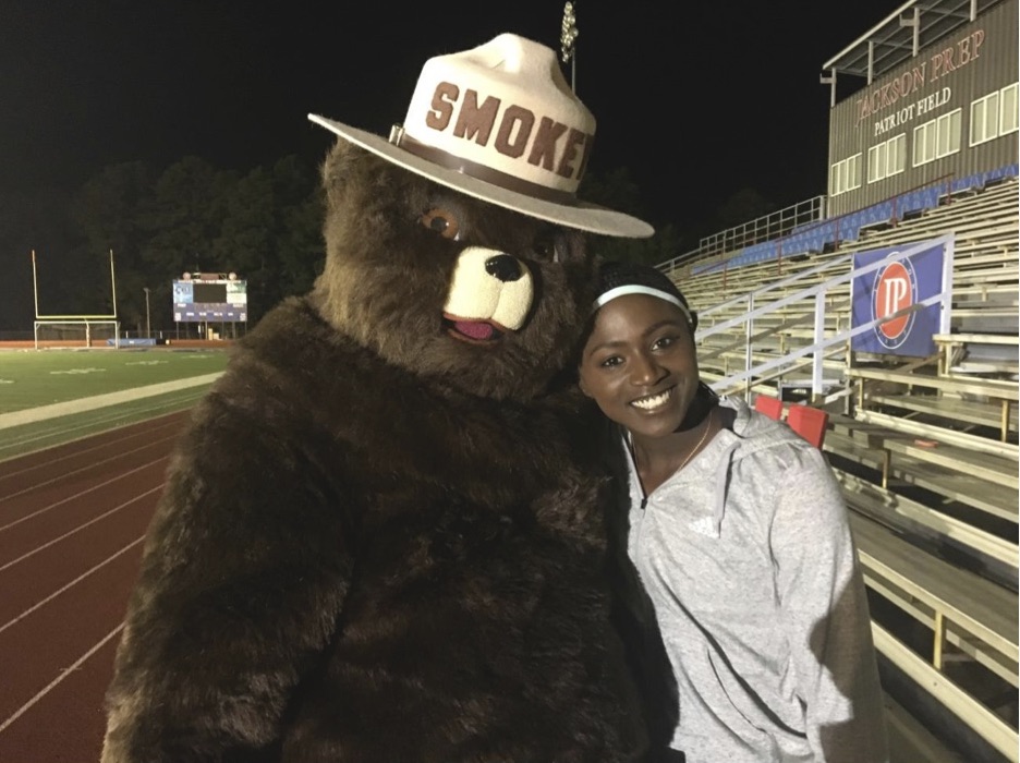 Tori Bowie standing on a running track next to Smokey Bear