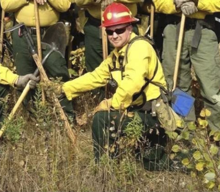 A man kneeling in front of a row of men, posing with shovels for a portrait