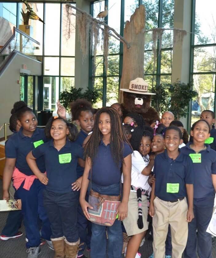 A group of children with Smokey Bear behind them.
