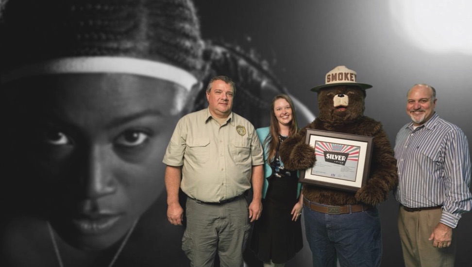 From left: Bill Kitchings (Outreach Officer, MFC), Brighton Forester (Public Relations Director, MFC), Smokey Bear, and Chip Sarver (President, Mad Genius)